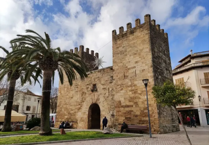 Puerta de Alcudia, Valencia, con palmeras y cielo azul.