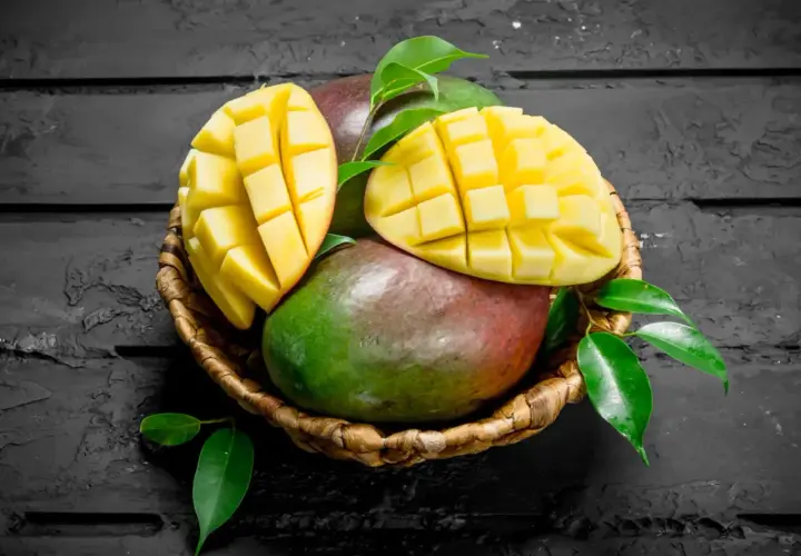 Koszyk z dojrzałymi mango, jedno przekrojone w kostkę. Czy zastanawiałeś się nad mango indeks glikemiczny?