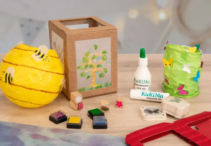 Bastelmaterialien für eine St. Martin Laterne: Bienen-Laterne, Baum-Laterne, Kleber, Stempel und Schmetterlingsstanzer.