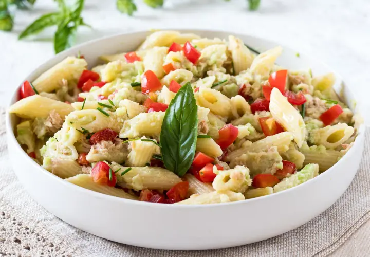 Penne con tonno e avocado, un piatto fresco e colorato con pomodorini e basilico.