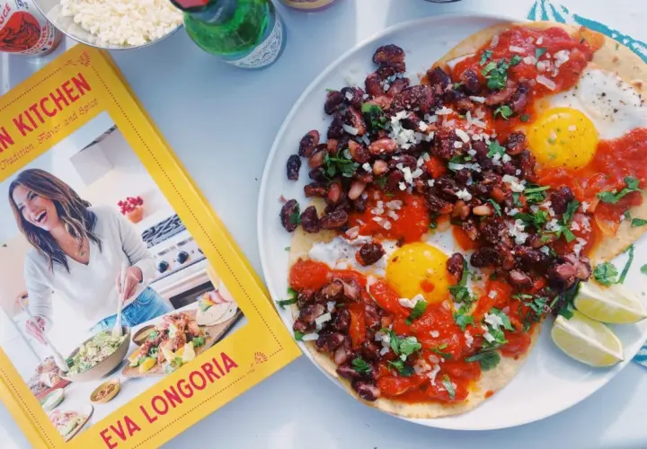 Deux œufs sur le plat, haricots noirs et sauce tomate sur tortillas, inspirés par le livre "Mexican Kitchen" d'Eva Longoria. Un plat de huevos rancheros savoureux.