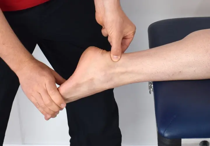 Mains appliquant un massage sur le tendon d'Achille d'une cheville.