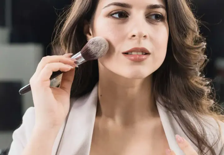 Donna applica il primer con un pennello, creando una base perfetta per il trucco.