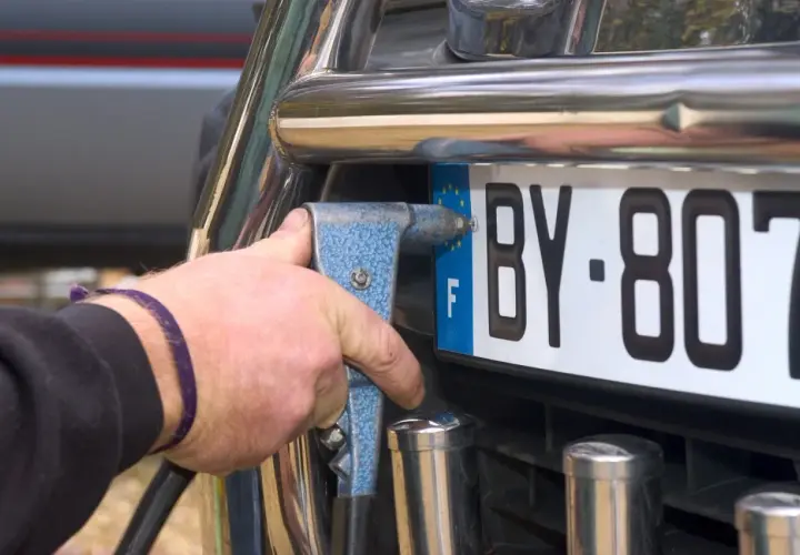 Mano con rivettatrice che fissa una targa auto, forse per cambiare targa auto per sfizio.