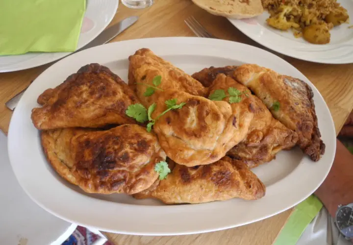 En tallrik med gyllene, friterade samosas, perfekt för ett samosa recept. Garnerade med färsk koriander.