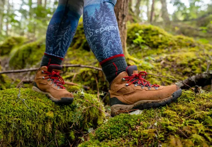 Hiking boots on mossy ground. Learn how to know if boots are too big by checking for heel slip and toe room.