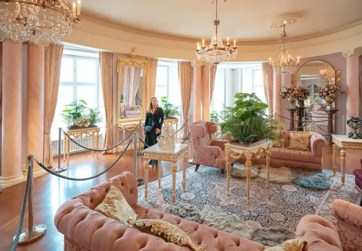 Elegancki salon z różowymi sofami i kryształowymi żyrandolami. Marzenie o noclegu w zamku staje się rzeczywistością.