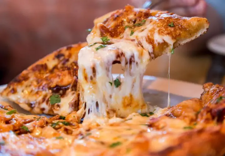Ein Stück Pizza mit geschmolzenem Käse wird hochgehoben. Die vielen Pizza Kalorien sind es wert!