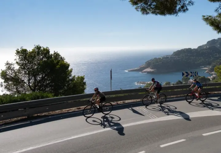 Ciclistas disfrutan del cicloturismo en Girona, con vistas al mar Mediterráneo y la costa.