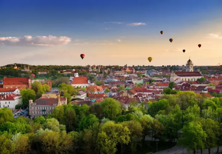 Widok na Wilno z lotu ptaka, z kilkoma balonami na gorące powietrze na niebie.