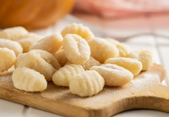 Gnocchis faits maison sur une planche en bois. La question "quelle pomme de terre pour gnocchi" est résolue avec ces petites bouchées parfaites.