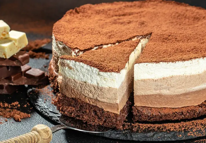 Tarta tres chocolates, con capas de mousse de chocolate blanco, con leche y negro, espolvoreada con cacao.