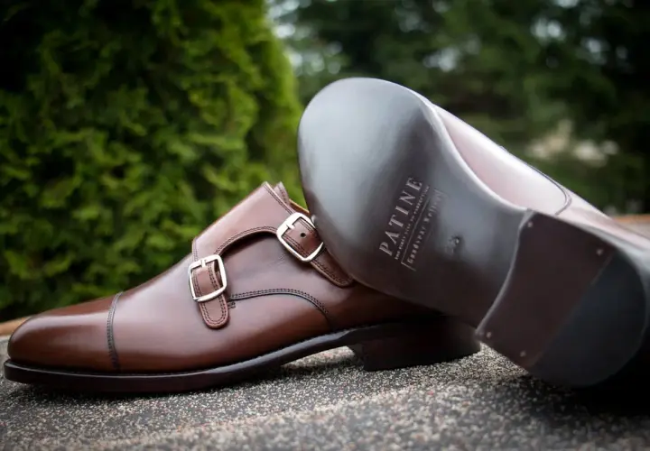 Eleganckie brązowe buty z podwójnymi klamrami, wykonane z wysokiej jakości kruponu. Widoczna podeszwa z logo marki.