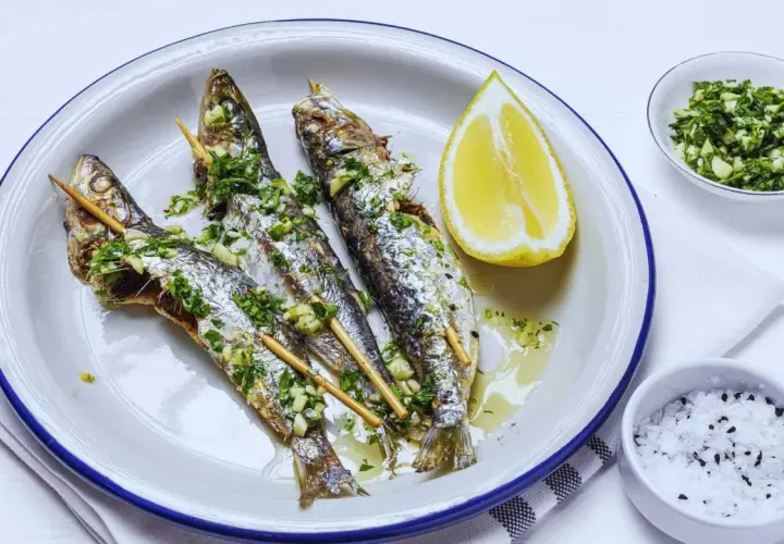Tres sardinas a la plancha, doradas y jugosas, con perejil y ajo picado, acompañadas de limón y sal.