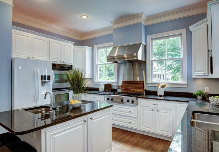 A bright kitchen with white cabinets and granite countertops. Learn how to care for granite to keep it looking its best.