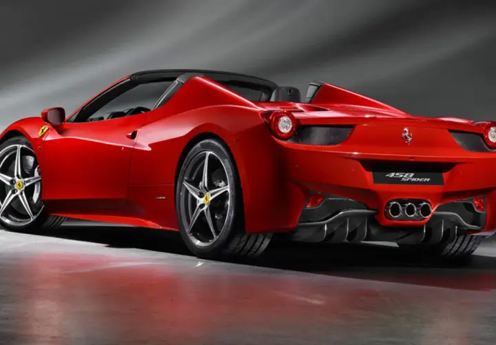 Czerwony kabriolet Ferrari 458 Spider z opuszczonym dachem, prezentujący swoje sportowe linie i potężne tylne światła.