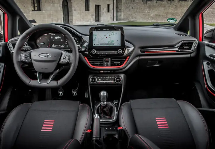 Interior deportivo del Ford Fiesta ST Line. Volante, asientos y detalles rojos resaltan en este habitáculo moderno.