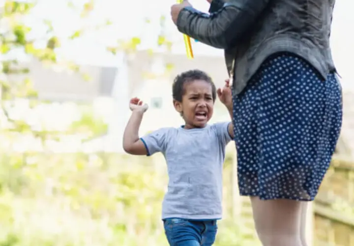 Un niño de 4 años, mi hijo, no obedece y pega. Llora y se enfada mientras su madre intenta calmarlo.