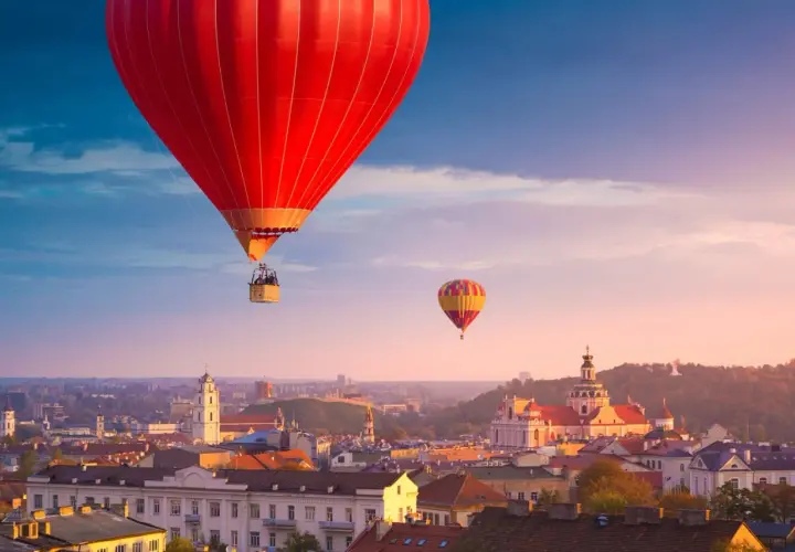 Widok na Wilno z lotu ptaka. Dwa balony unoszą się nad miastem o zachodzie słońca, oferując niezapomniane wrażenia z podróży "Wilno w jeden dzień".