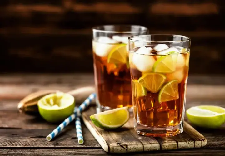 Dwa szklanki z lodem i plasterkami limonki, idealne orzeźwiające drinki na upalny dzień.