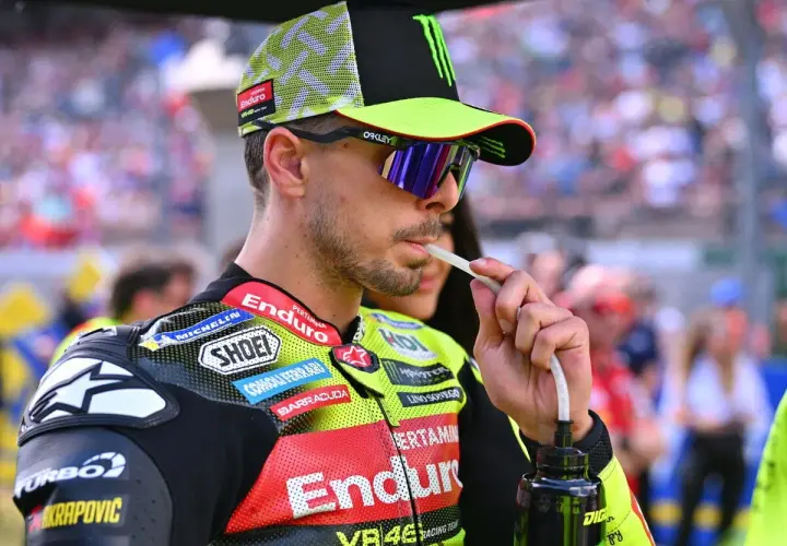 Fabio Di Giannantonio, piloto de MotoGP, bebe de una botella con un tubo, luciendo su casco y gafas de sol.