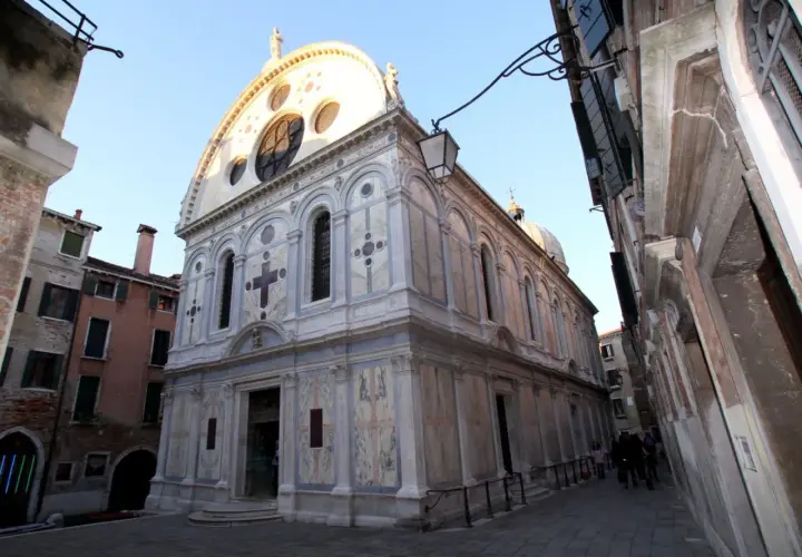 La façade en marbre de Santa Maria dei Miracoli à Venise, ornée d'une grande rosace et d'une croix.