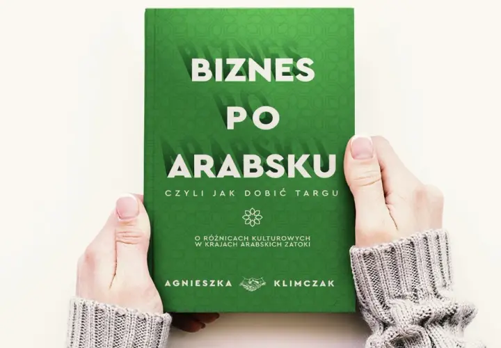 Dwie dłonie trzymają zieloną książkę z białym napisem "Biznes po arabsku".