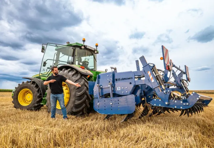 Un homme présente une charrue Rolmako, un outil agricole essentiel pour préparer les sols. La sep charrue définition est ici illustrée par cet équipement robuste.