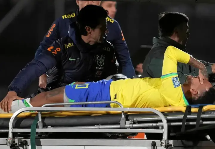 Neymar leży na noszach, z bólu trzymając się za twarz. Jego **neymar kontuzja** wygląda poważnie, a sztab medyczny otacza go troską.