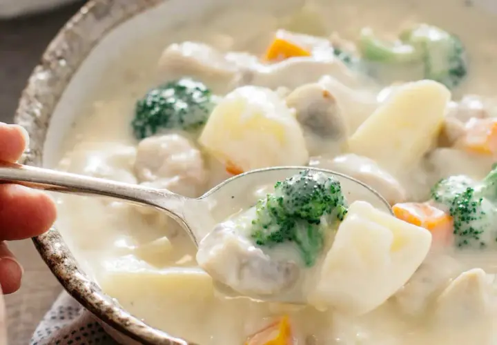 A spoonful of creamy Japanese white stew, filled with tender chicken, potatoes, broccoli, and carrots, ready to be savored.