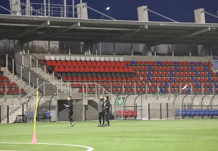 Piłkarze Polonii Bytom trenują na nowym stadionie. Puste trybuny z czerwonymi i niebieskimi krzesełkami czekają na kibiców.