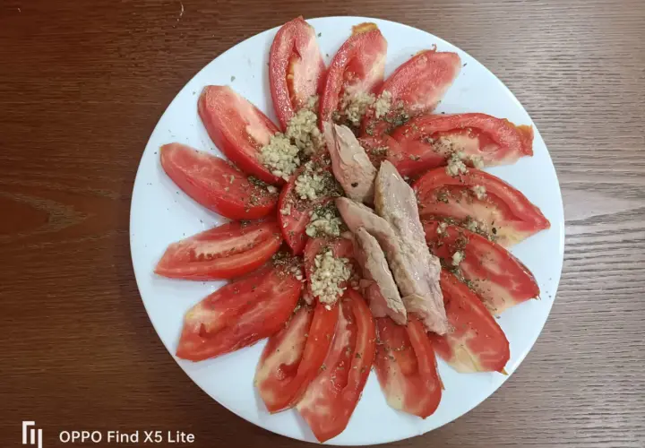 Rodajas de tomate fresco aliñado con ajo picado y hierbas, coronado con trozos de melva. Un plato sencillo y delicioso.