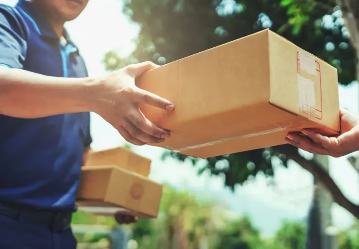 Ein Lieferant übergibt ein Paket. Hoffentlich ist das Paket angekommen und nicht verloren gegangen.