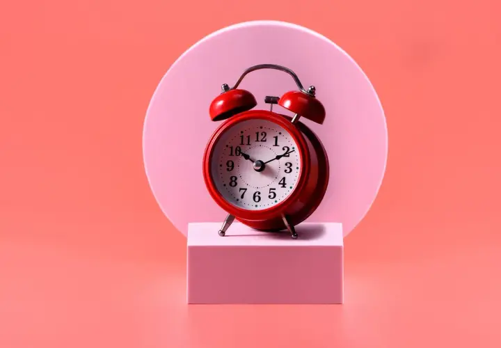 Reloj rojo sobre pedestal rosa. El 0909 significado espiritual nos recuerda la importancia del tiempo y la conexión.