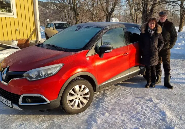 Ett par står bredvid en röd Renault Captur med frost på vindrutan. Kanske ett problem med att starta bilen i kylan?
