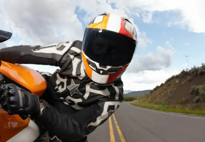 Motociclista con casco y visera oscura, listo para una multa por exceso de velocidad en la carretera.