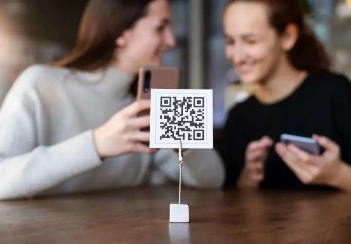 Dwie dziewczyny próbują zeskanować kod QR aparatem telefonu. Proste jak budowa cepa!