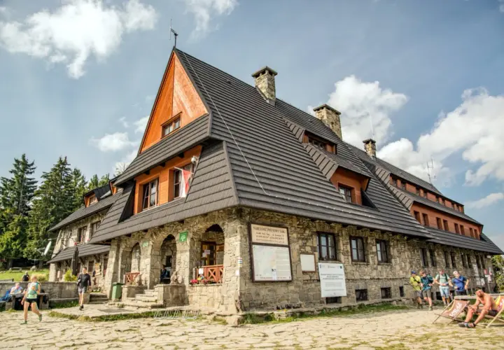 Schronisko PTTK na Turbaczu, popularne wśród turystów z Nowego Targu, z kamienną fasadą i drewnianymi elementami.