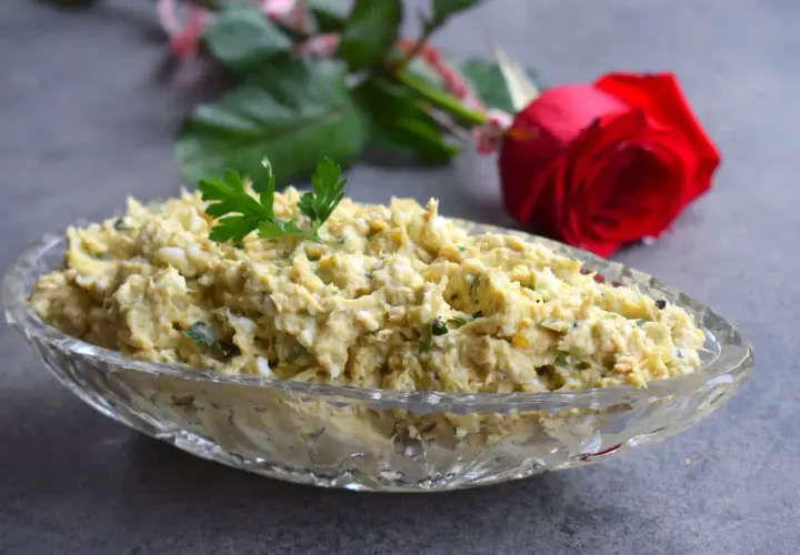 Pyszna pasta z awokado i tuńczyka, udekorowana natką pietruszki, w kryształowej misie. W tle czerwona róża.