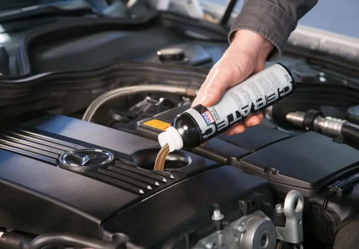 Dłoń wlewa płyn spulung liqui moly do silnika samochodu.