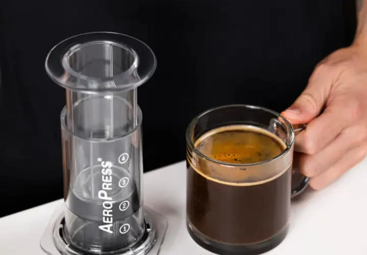 AeroPress gotowy do zaparzenia idealnego espresso. Obok filiżanka aromatycznej kawy.