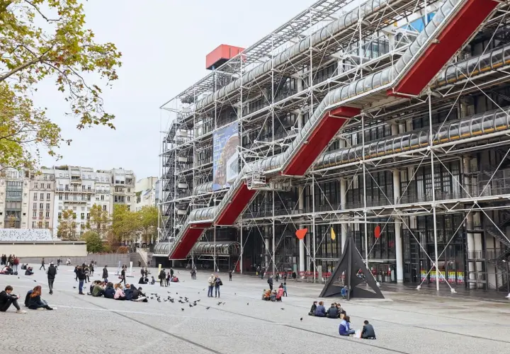 Centrum Pompidou w Paryżu z czerwonymi schodami ruchomymi i ludźmi na placu.