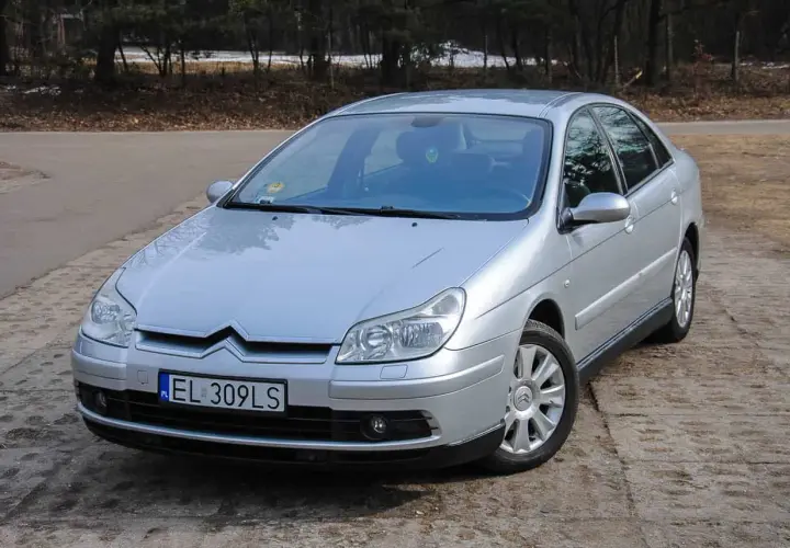 Srebrny Citroen C5 2.0 HDi zaparkowany na drodze leśnej.