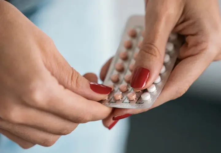 Hände halten eine Blisterpackung mit Pillen, darunter eine Drospirenon Pille.