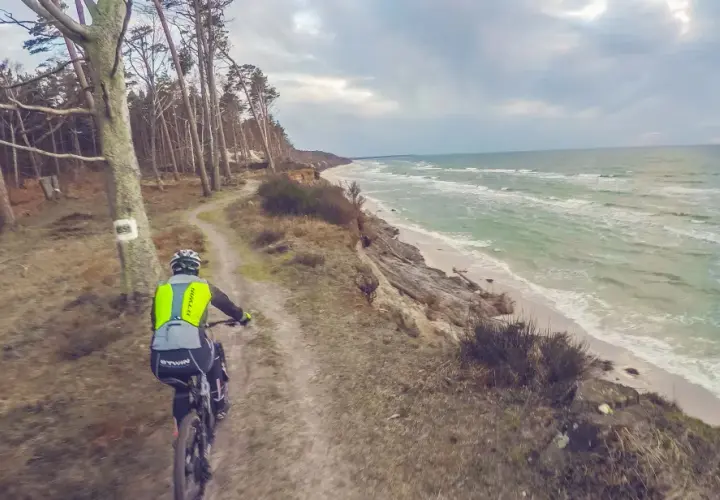 Rowerzysta na ścieżce przy klifie, w tle morze. Trasa rowerowa w okolicach Słupska.