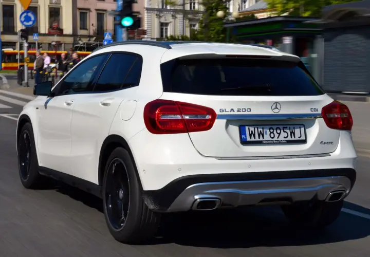 Biały Mercedes GLA 200 na polskich tablicach rejestracyjnych jedzie ulicą miasta.