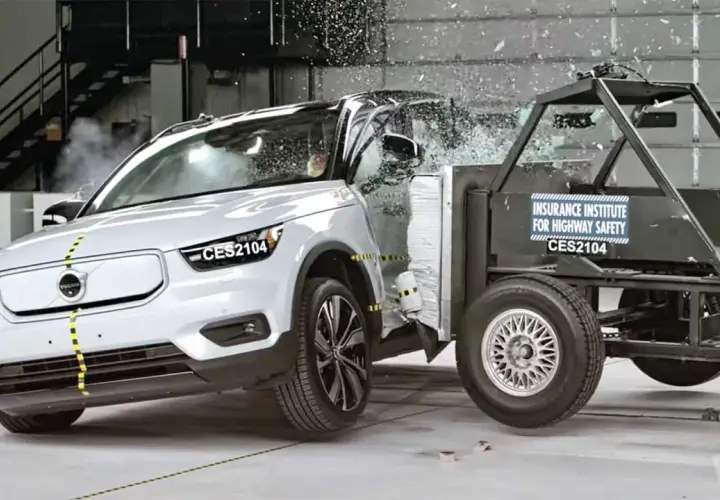 En vit Volvo XC40 krocktestas mot en barriär. Glas splittras och bilen deformeras vid kollisionen.