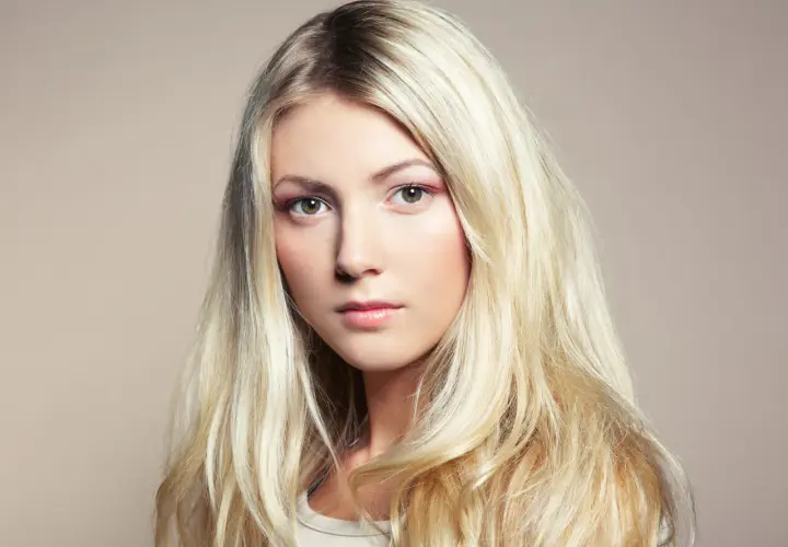 Piękna blondynka z długimi, falowanymi włosami. Poznaj sekrety, jak dbać o blond włosy, by były zdrowe i lśniące.