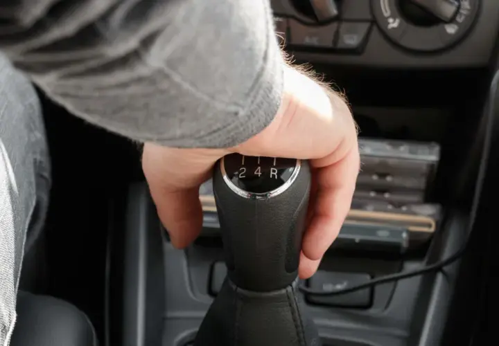 Mano cambiando de marcha en un coche, se escucha un ruido al girar el volante en movimiento a la derecha.