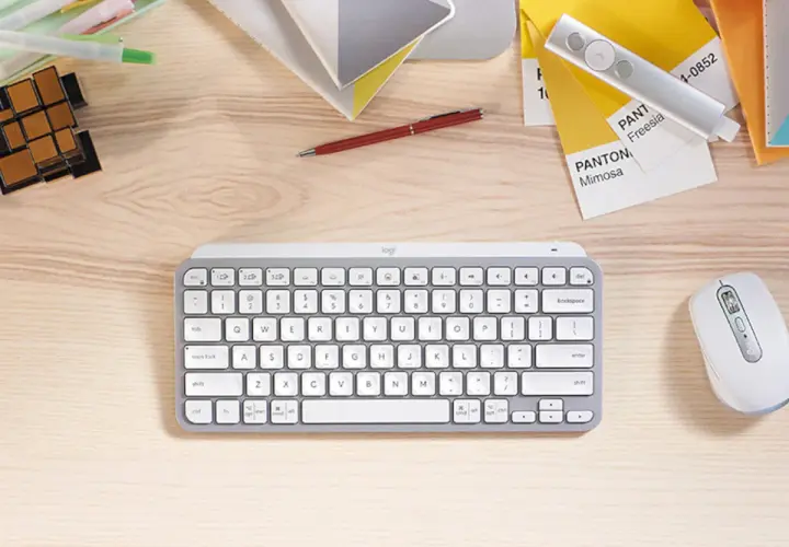 Escritorio con varios tipos de teclado, ratón, bolígrafo, cubos y muestras de color Pantone.